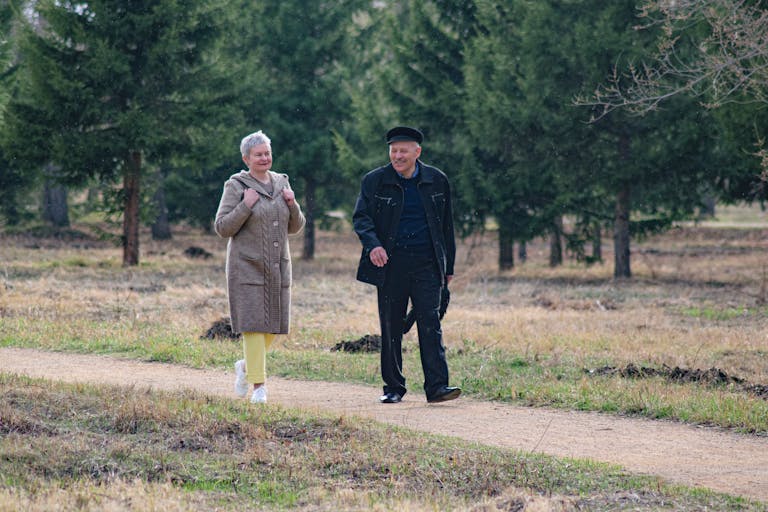 Happy senior couple strolling along a park path on a pleasant spring day.